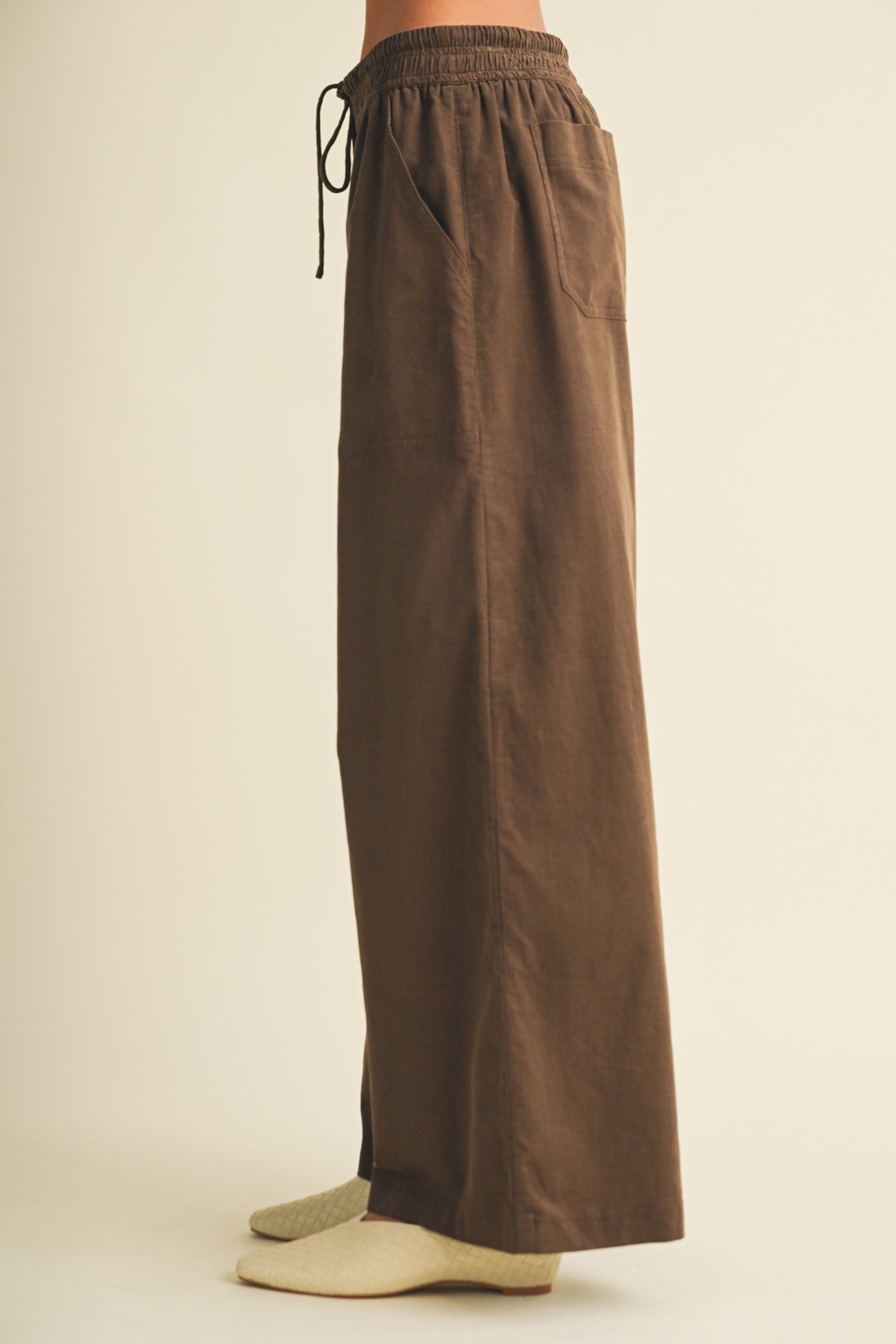 woman wearing brown wide-leg pants with an elastic waistband and pockets, styled with gray socks