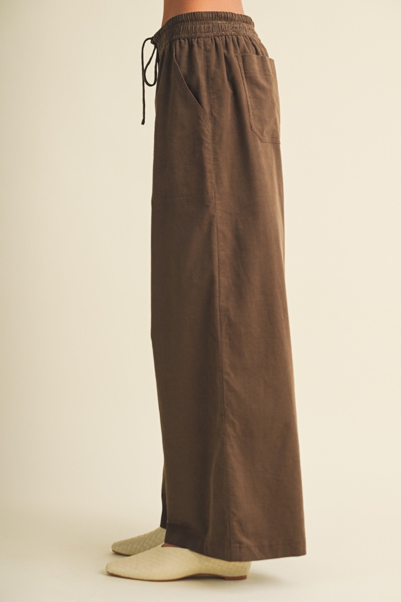 woman wearing brown wide-leg pants with an elastic waistband and pockets, styled with gray socks