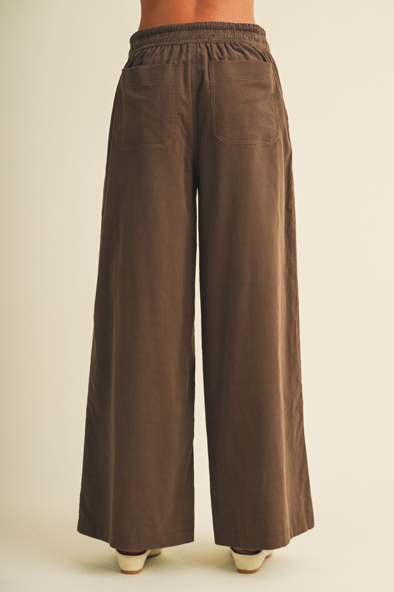 woman wearing brown wide-leg pants with an elastic waistband and two back pockets