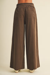 woman wearing brown wide-leg pants with an elastic waistband and two back pockets