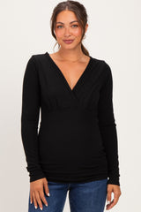 woman wearing a black long sleeve maternity top with a v-neck and fitted style, showing her baby bump