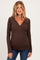 woman wearing a brown long sleeve maternity top with a v-neck and slight ruching at the sides