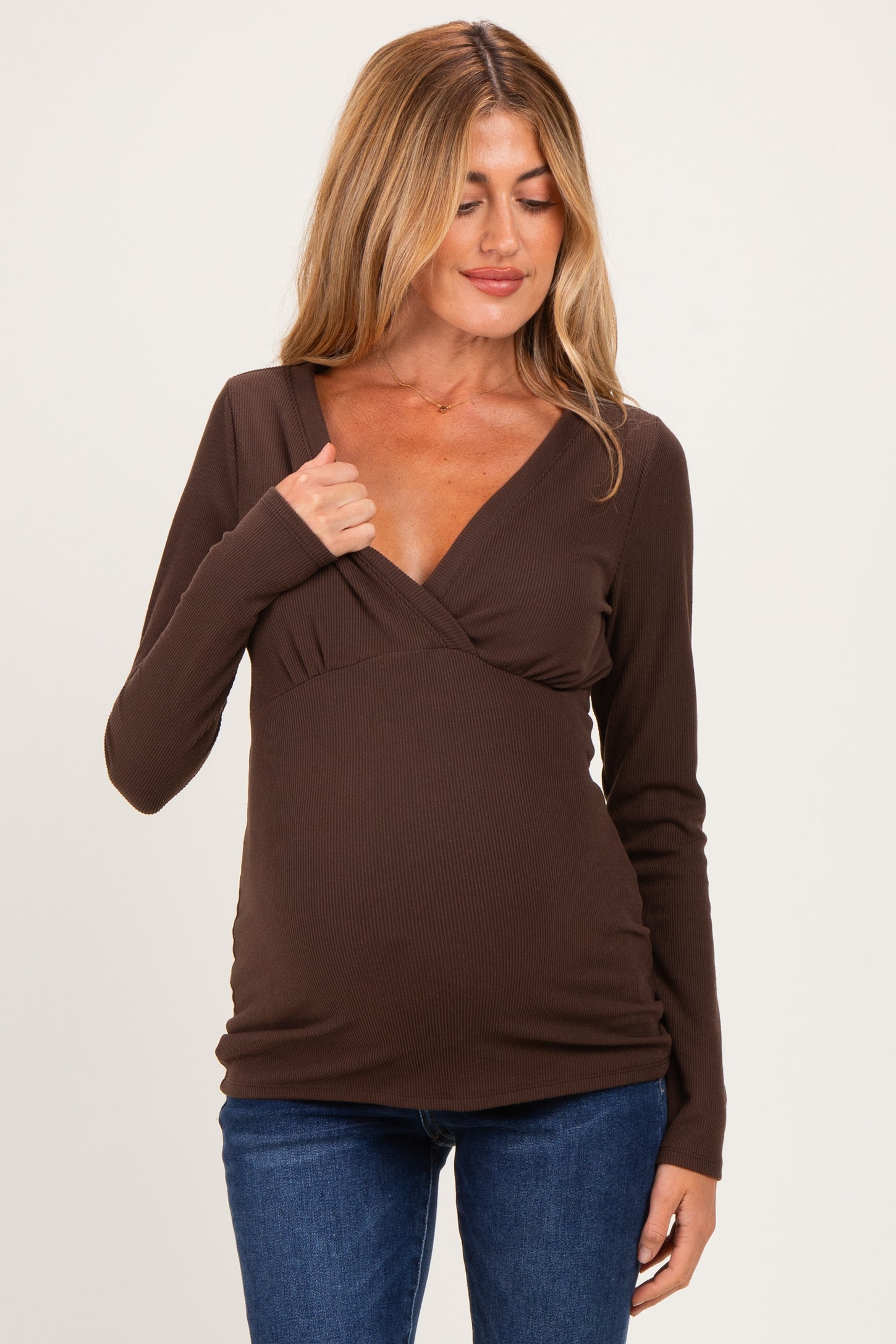 woman wearing a brown long sleeve maternity top with a v-neck and ruched sides, showing her baby bump