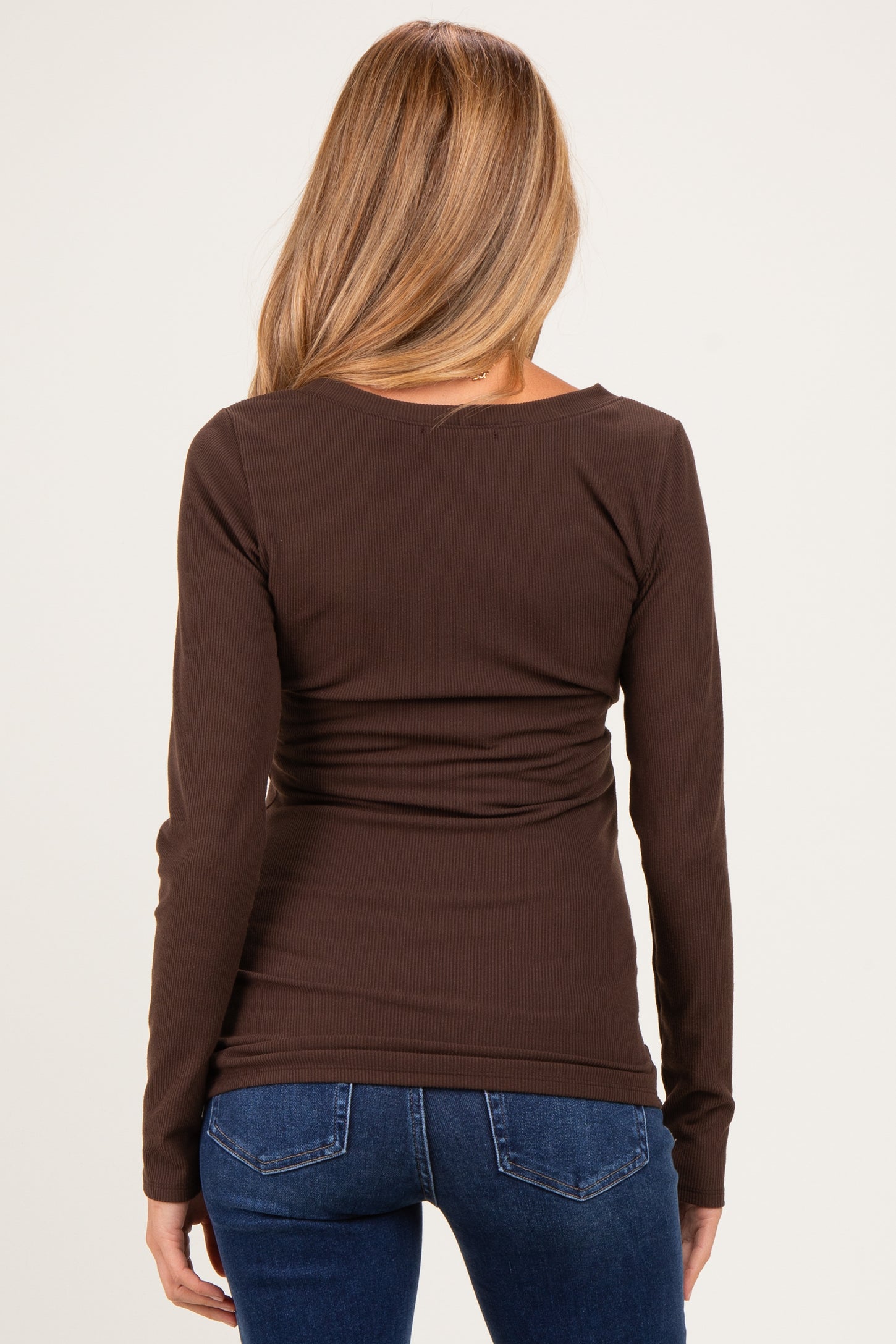 woman wearing a brown maternity top with a fitted silhouette and long sleeves, seen from the back