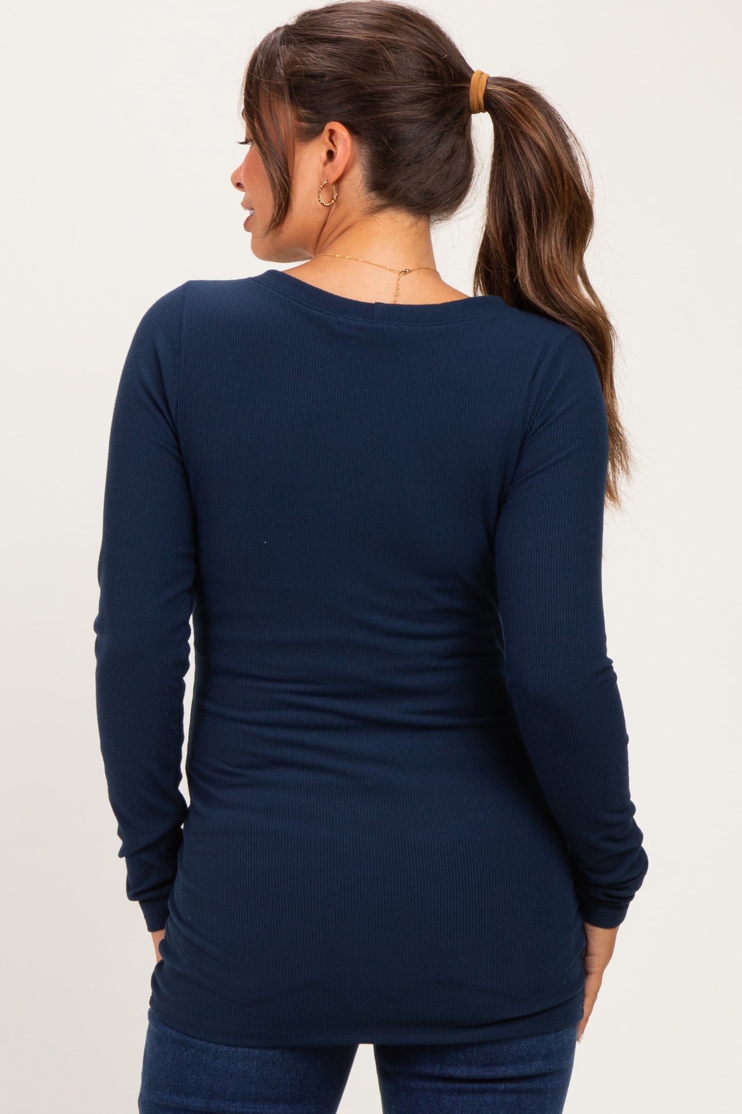 woman wearing a navy blue long sleeve maternity top, showing gathered details at the back