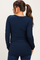 woman wearing a navy blue long sleeve maternity top, showing gathered details at the back