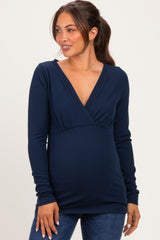 woman wearing a navy blue long sleeve maternity top with a v-neck and a visible baby bump