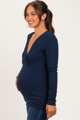 woman wearing a navy blue long sleeve maternity top with a v-neck and holding her baby bump
