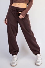 woman wearing brown high-waisted joggers with side pockets and elastic cuffs, paired with white sneakers