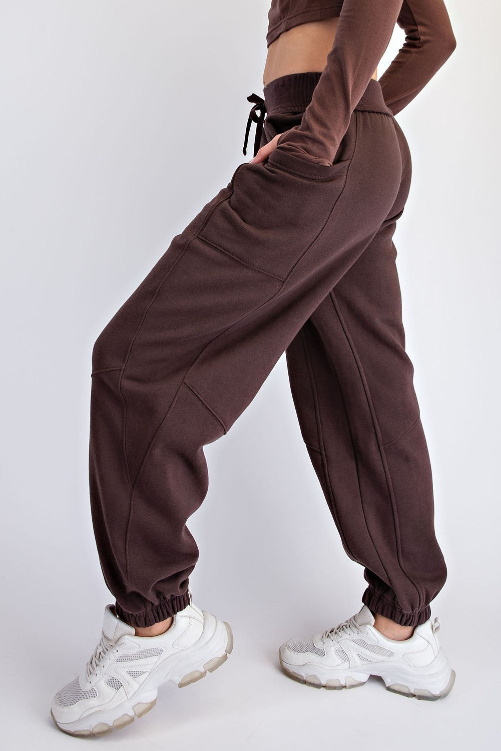 woman wearing dark brown high-waisted joggers with side pockets and elastic cuffs