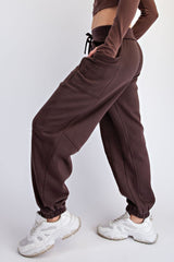 woman wearing dark brown high-waisted joggers with side pockets and elastic cuffs