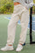 woman wearing cream-colored jogger pants with elastic cuffs and side pockets, standing on a tennis court