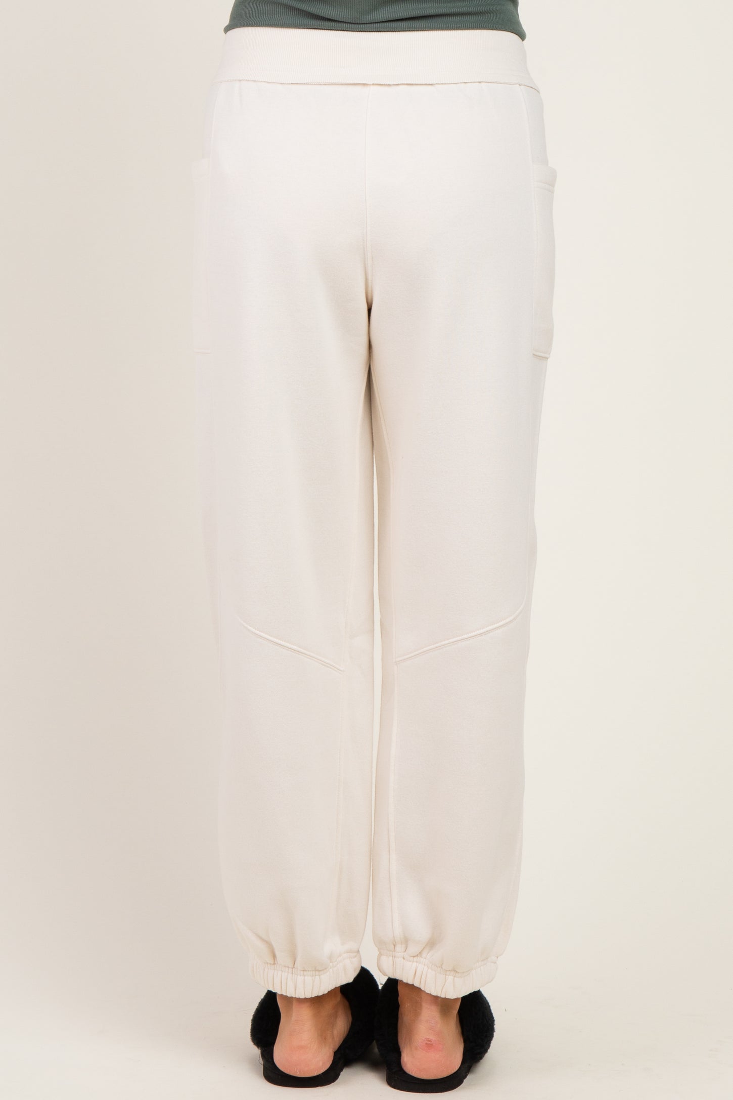 woman wearing cream colored maternity jogger pants with elastic cuffs and side pockets, viewed from the back