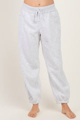 woman wearing light grey sweatpants with elastic cuffs and adjustable drawstring waistband, standing barefoot