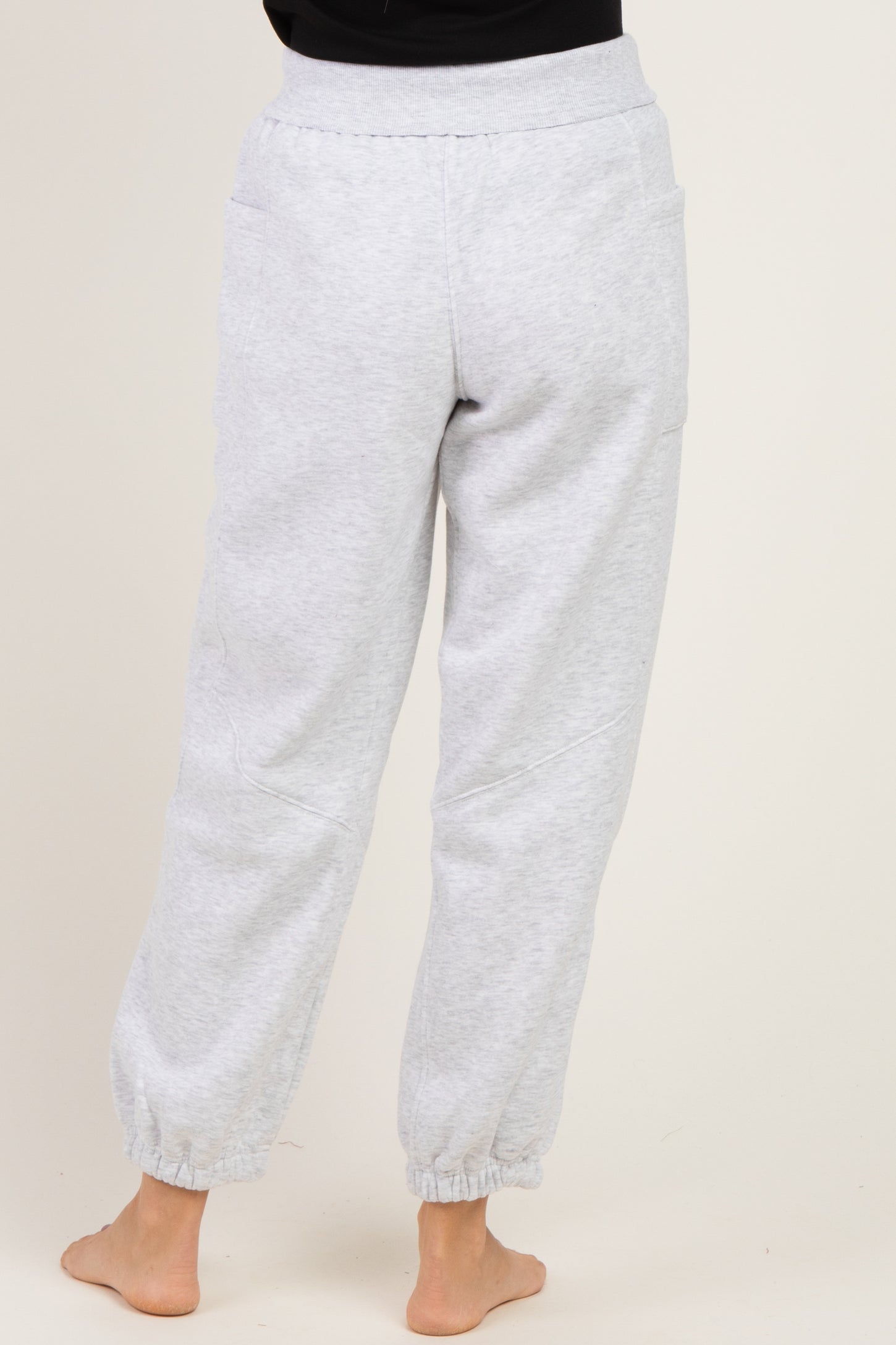woman wearing light gray sweatpants with elastic cuffs and pockets, viewed from the back