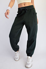 woman wearing dark green jogger pants with a relaxed fit and elastic ankle cuffs, styled with a fitted crop top