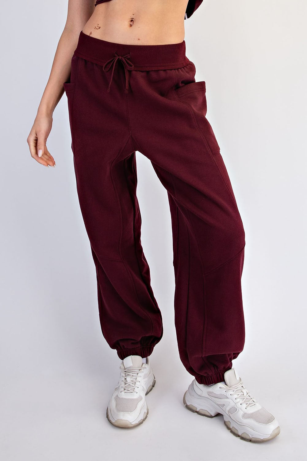woman wearing burgundy loose-fit jogger pants with side pockets and elastic cuffs, paired with white sneakers