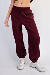 woman wearing burgundy loose-fit jogger pants with side pockets and elastic cuffs, paired with white sneakers