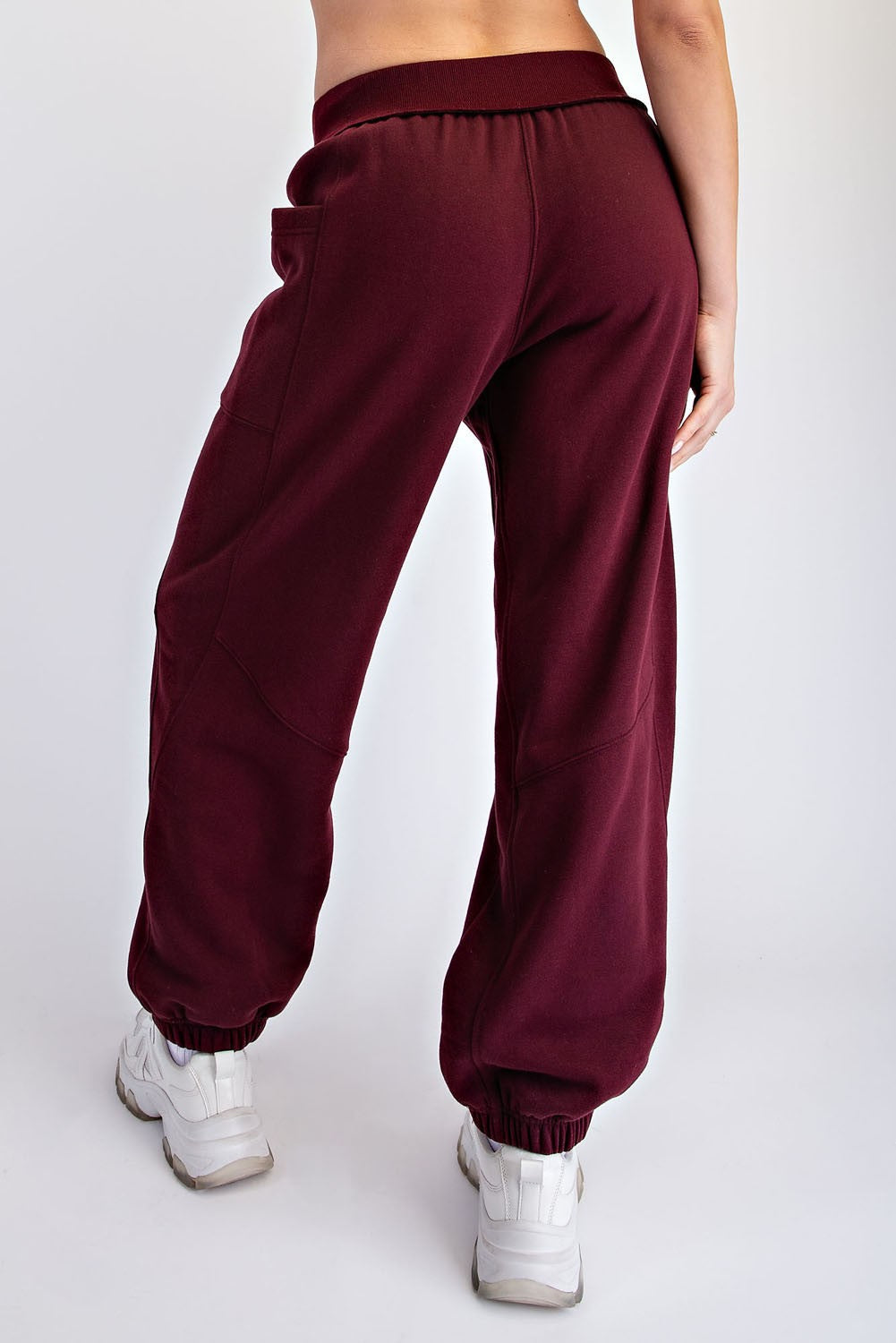 woman wearing burgundy jogger pants with an elastic waistband and cuffed ankles, seen from the back
