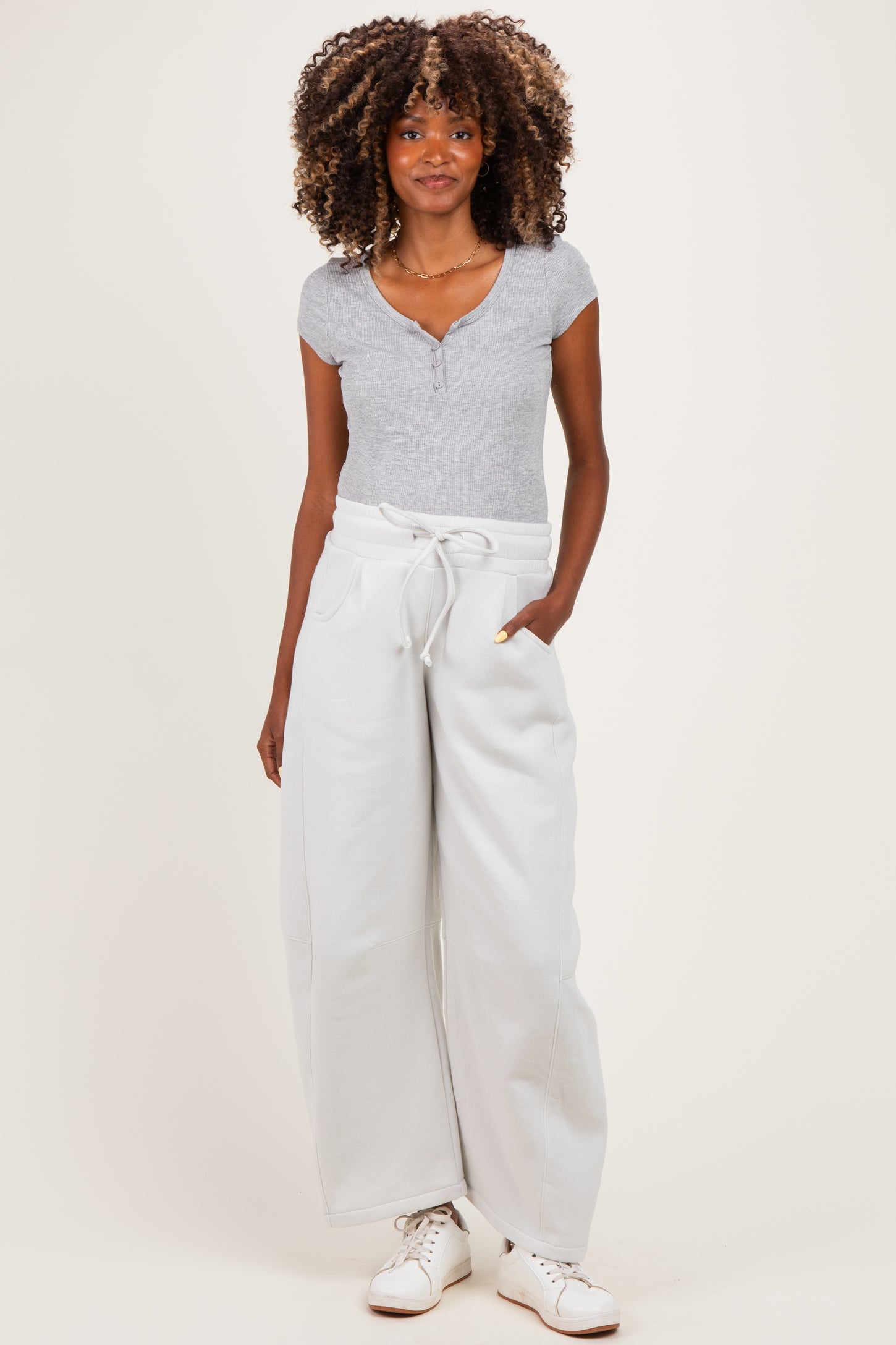 woman wearing a gray maternity henley top and light gray wide-leg sweatpants with pockets