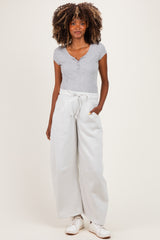 woman wearing a gray maternity henley top and light gray wide-leg sweatpants with pockets