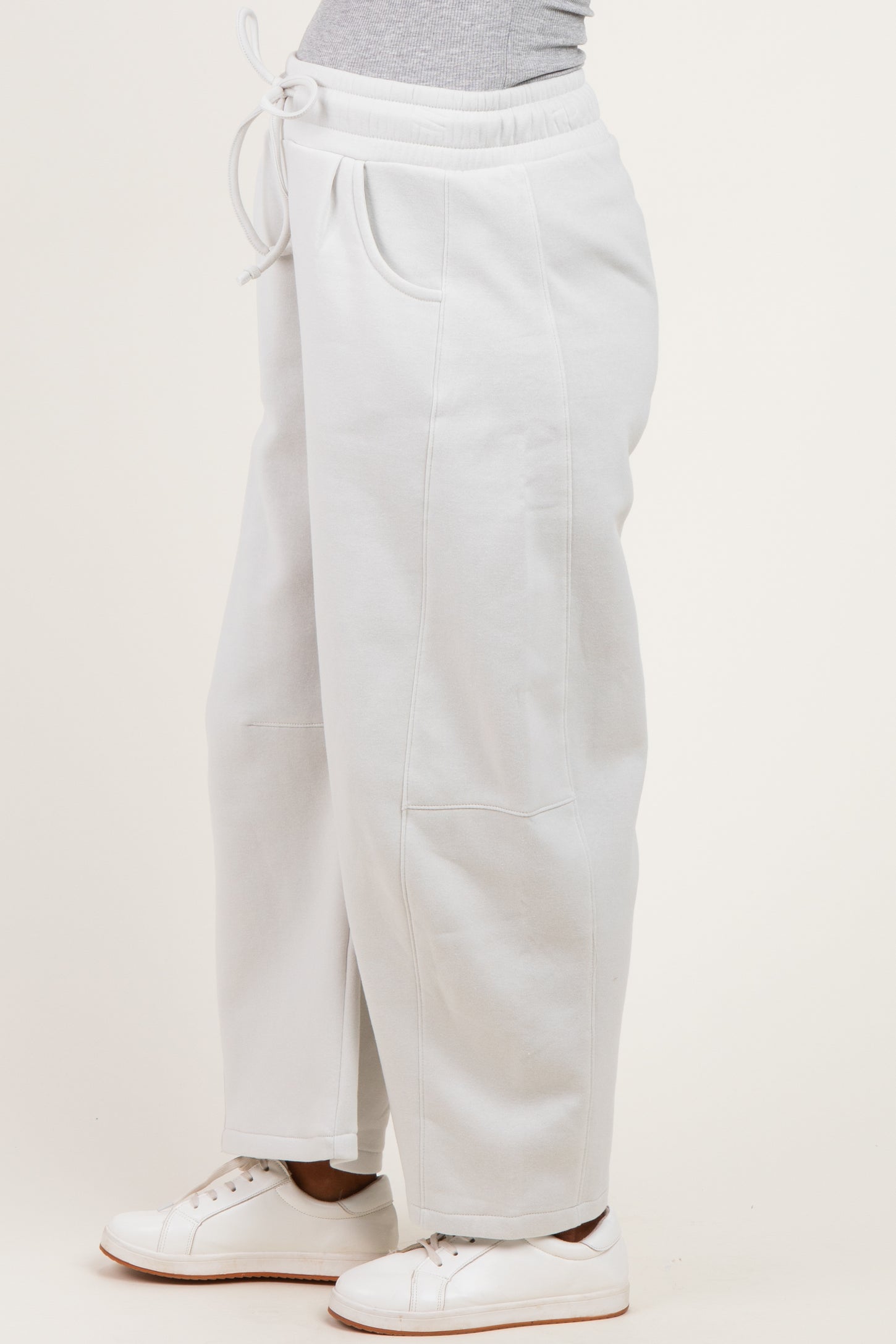 woman wearing light gray maternity sweatpants with a drawstring waist and side pockets.