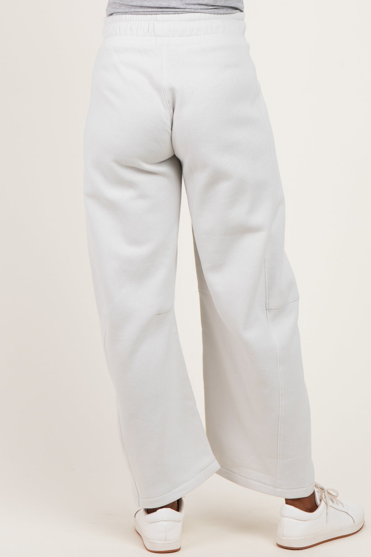 woman wearing light gray maternity sweatpants with a wide leg and elastic waistband, showing a relaxed fit from the back