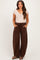 woman wearing a light brown short sleeve henley top and dark brown wide-leg maternity sweatpants with pockets