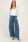 woman wearing a white long sleeve maternity top and blue wide-leg maternity pants with pockets