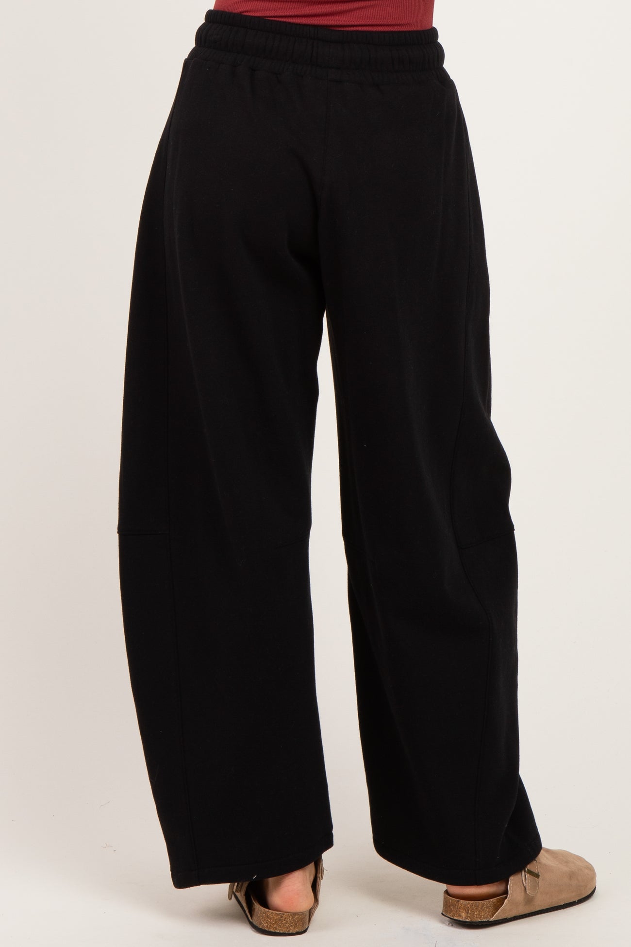 woman wearing black wide-leg sweatpants, shown from the back with a relaxed fit and elastic waistband