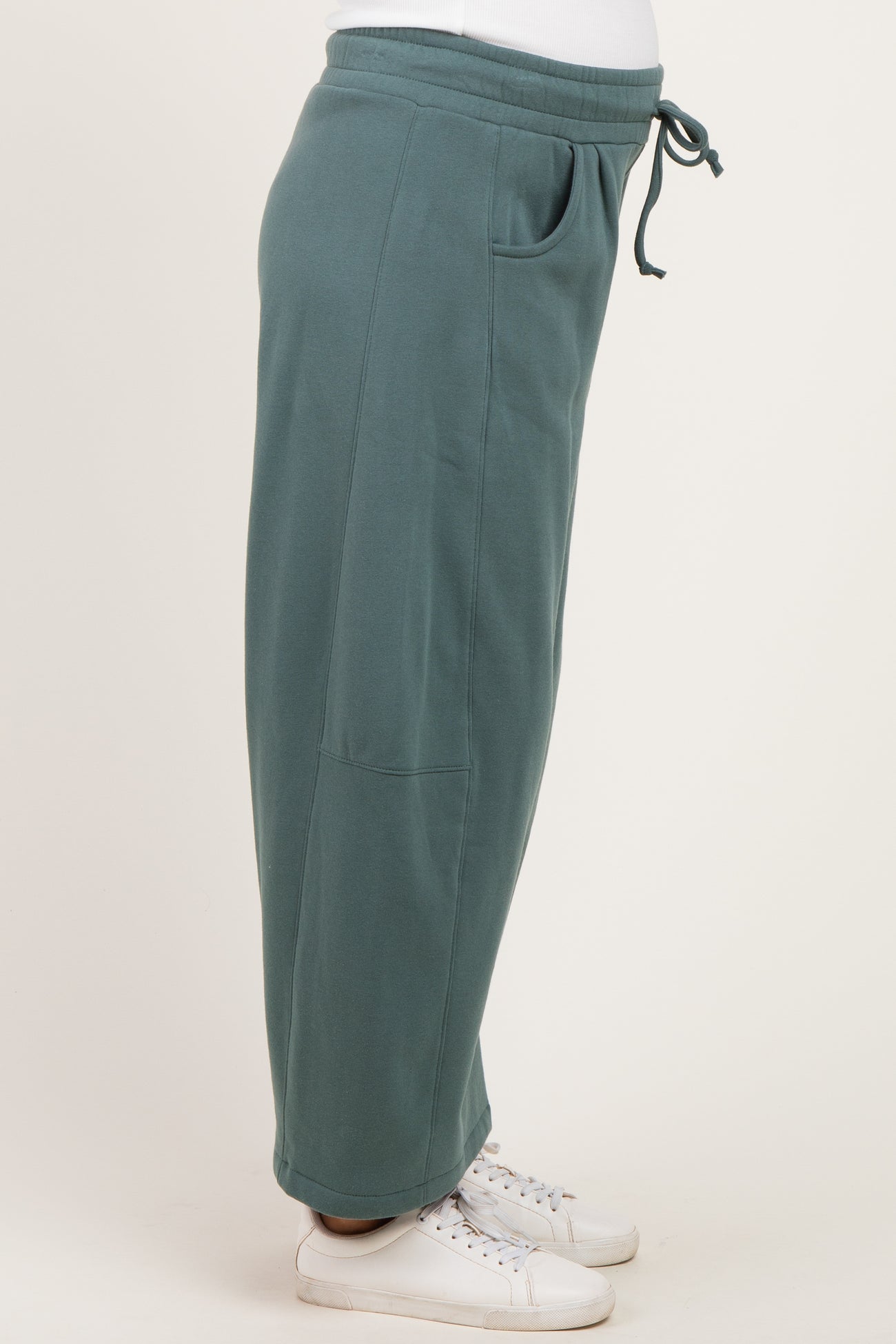 woman wearing a side view of a green maternity jogger pant with pockets and a drawstring waistband