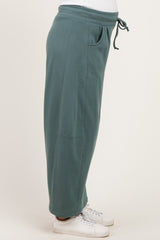 woman wearing a side view of a green maternity jogger pant with pockets and a drawstring waistband
