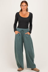 woman wearing a black long sleeve scoop neck top and green wide-leg sweatpants with pockets