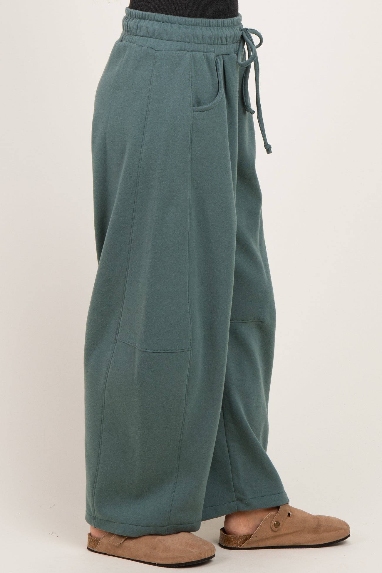 woman wearing oversized teal sweatpants with an elastic waistband and side pockets