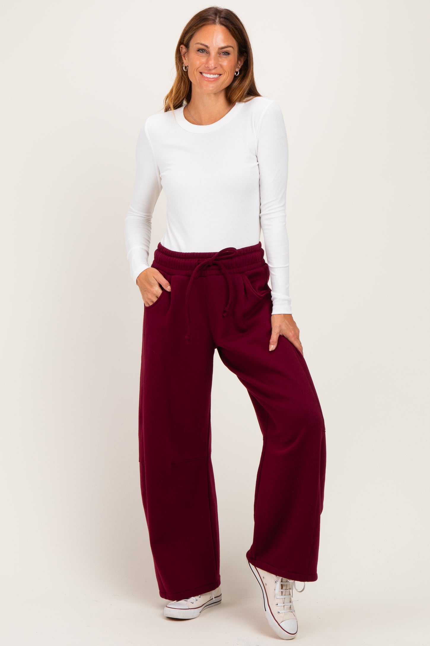 woman wearing a white long sleeve top and burgundy wide-leg pants with a drawstring waist