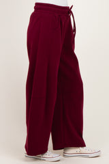 woman wearing burgundy wide-leg sweatpants with a drawstring waist and side pockets