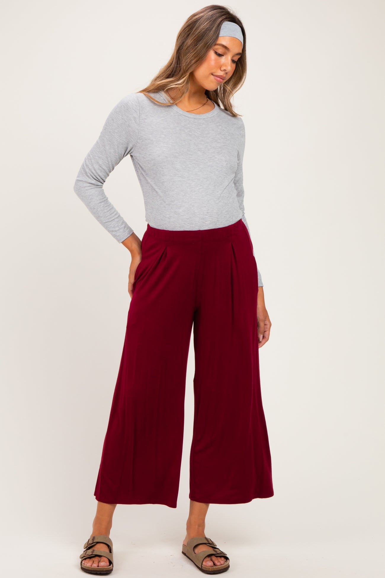 woman wearing a gray long sleeve maternity top and burgundy wide-leg maternity pants, with a relaxed fit and side pleats