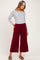 woman wearing a gray long sleeve maternity top and burgundy wide-leg maternity pants, with a relaxed fit and side pleats