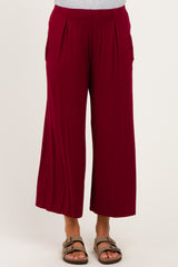 woman wearing a pair of burgundy maternity wide leg pants with pleat details