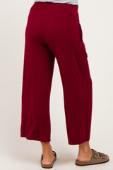 woman wearing burgundy maternity wide leg pants with pockets and sandals, seen from the back