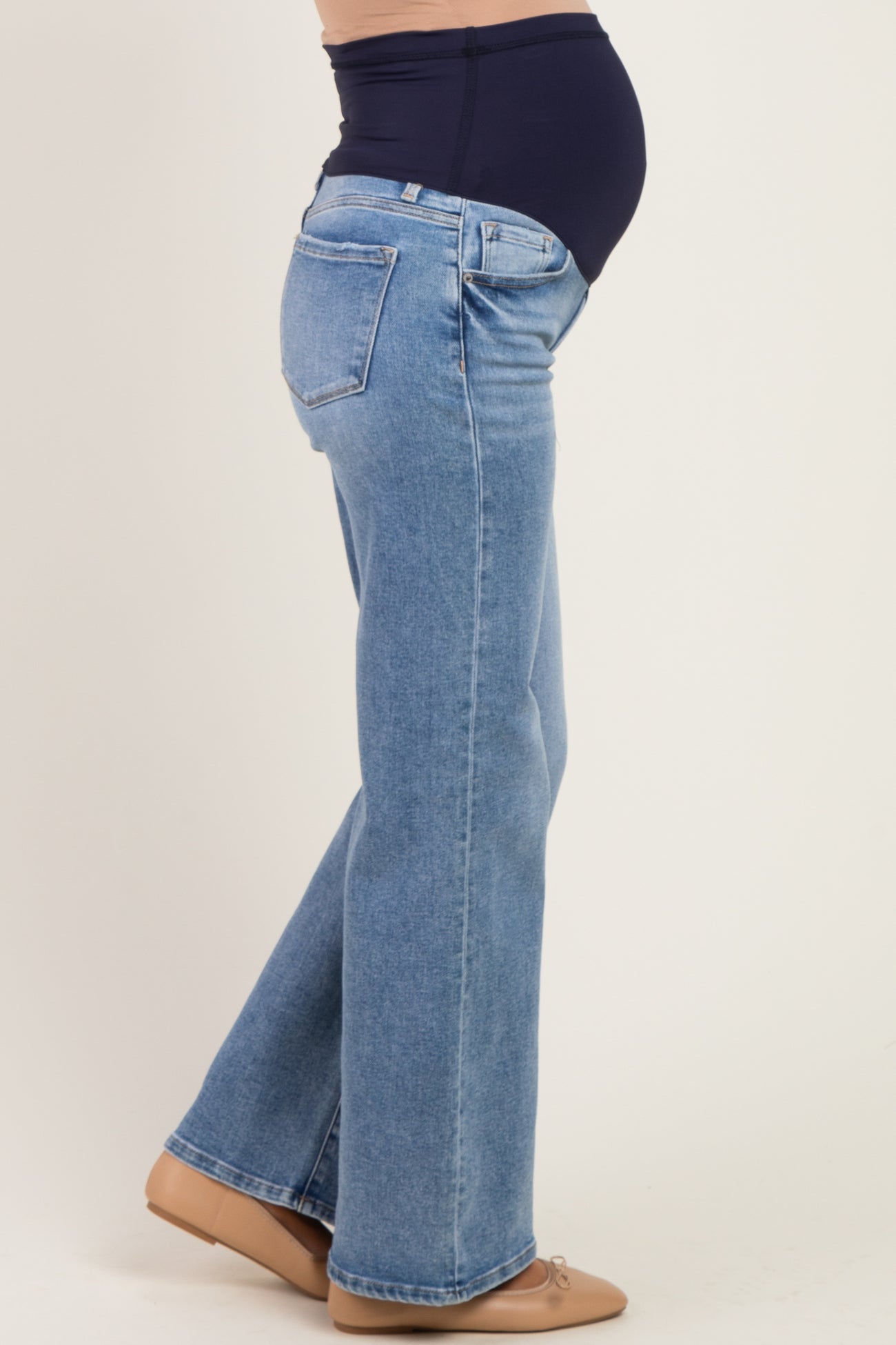 woman wearing light wash maternity jeans with a supportive belly band and visible baby bump.
