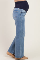 woman wearing light wash maternity jeans with a supportive belly band and visible baby bump.