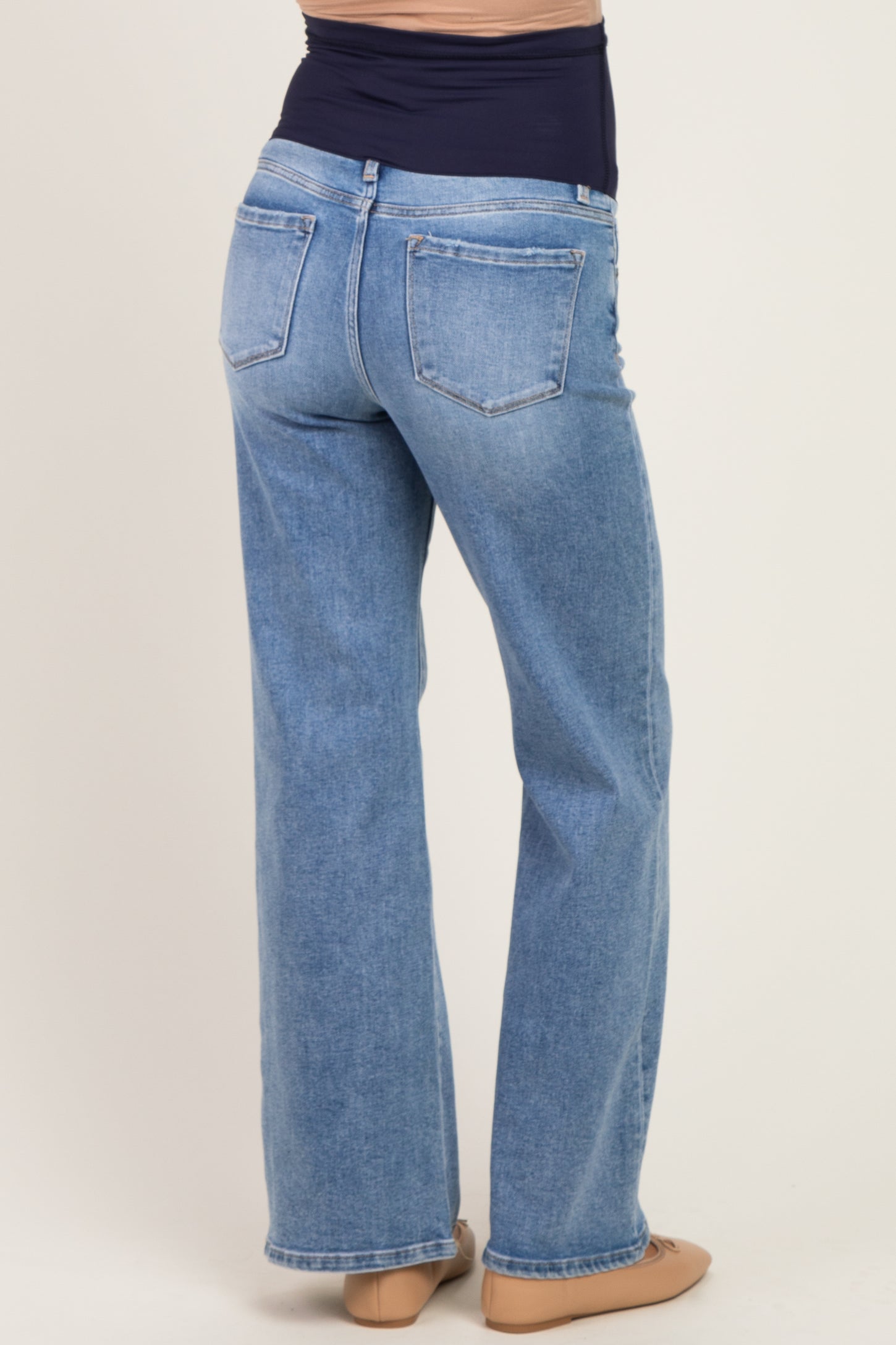 woman wearing light blue maternity jeans with a flared style, showing the back view and a supportive waistband