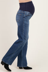 woman wearing a pair of dark blue maternity jeans with a fitted belly panel, showing her baby bump