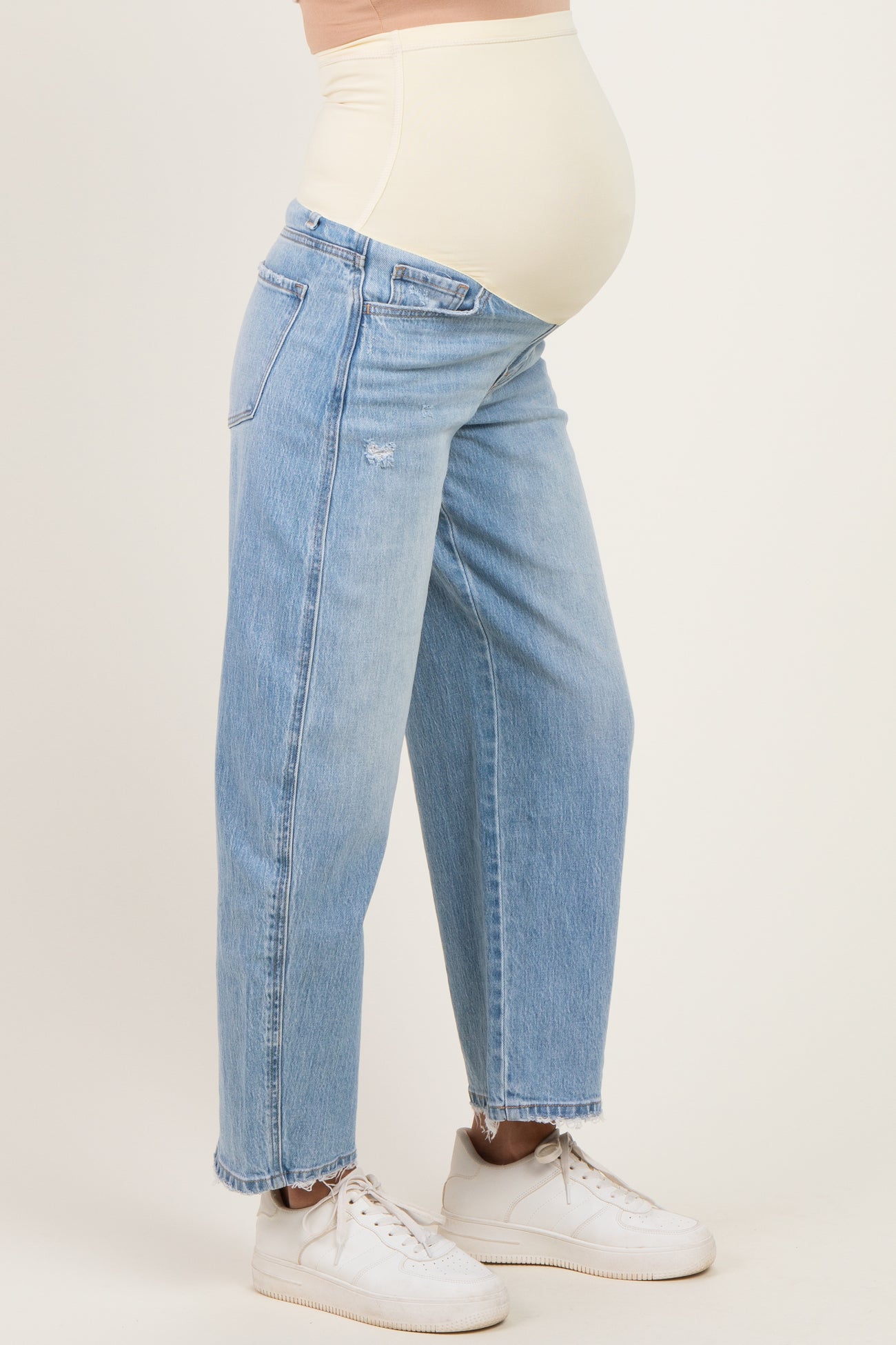 woman wearing light blue maternity jeans with a stretchy beige waist panel and a visible baby bump