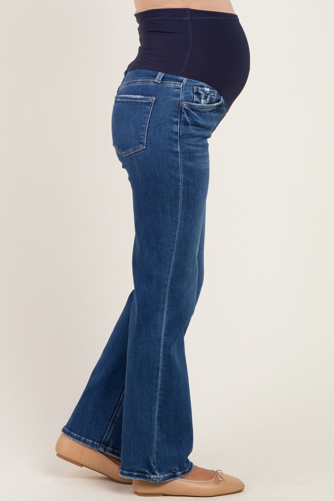 woman wearing dark blue maternity bootcut jeans with a supportive belly panel and a visible baby bump