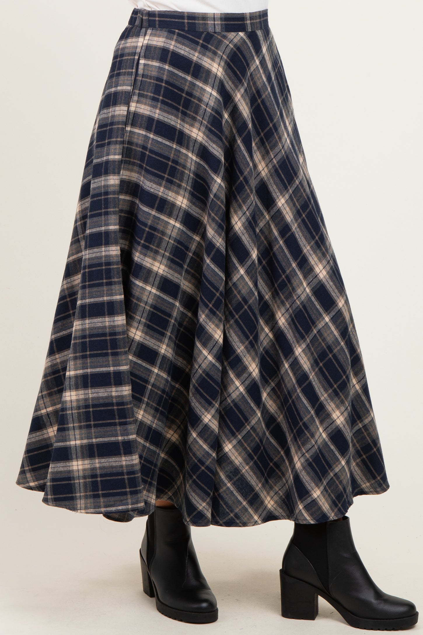 flared navy blue and tan plaid skirt with an A-line silhouette, styled with black ankle boots