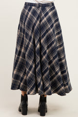 woman wearing a navy blue plaid midi skirt with pleats and black ankle boots, seen from the back