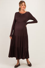 woman wearing a dark brown long sleeve maternity dress with tiered skirt and visible baby bump