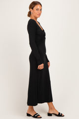 woman wearing a black long sleeve maxi dress with a twisted front detail and styled with black slide sandals